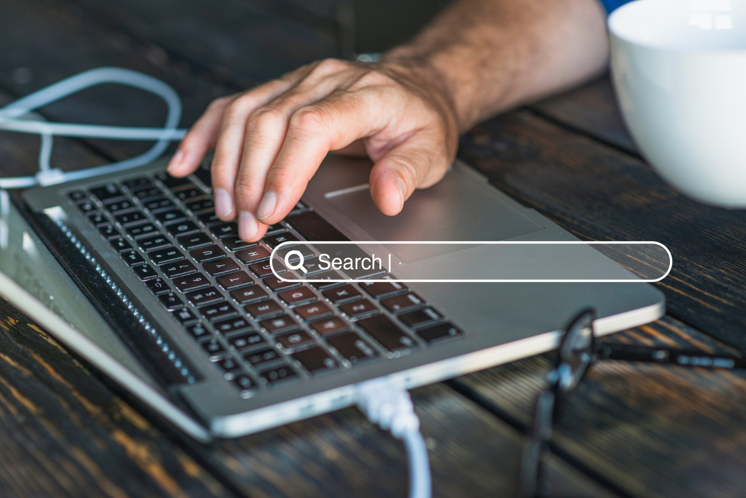 Close-up of a person using a laptop with a digital search bar overlay representing online visibility, SEO strategy, and how algorithms interpret brand